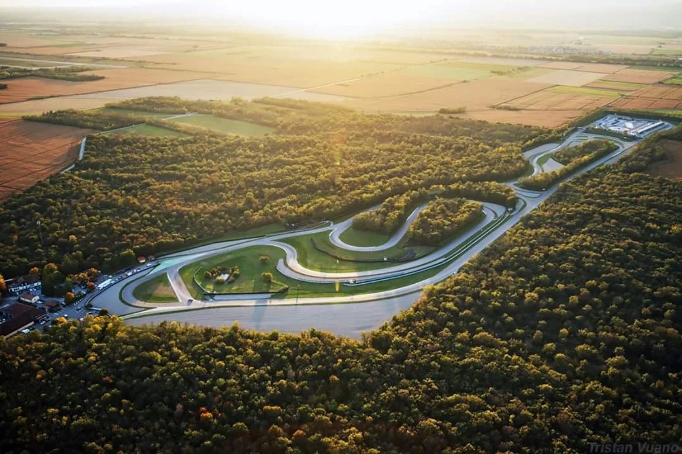 Vue aérienne du circuit au soleil couchant, son tracé sinueux au milieu des bois