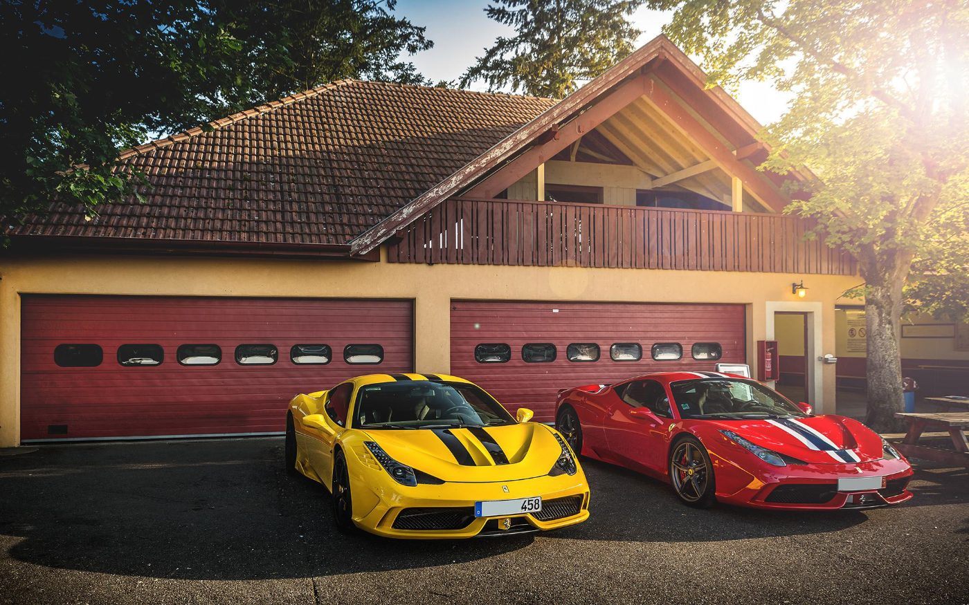 Voitures de membres alignées devant les garages du paddock club