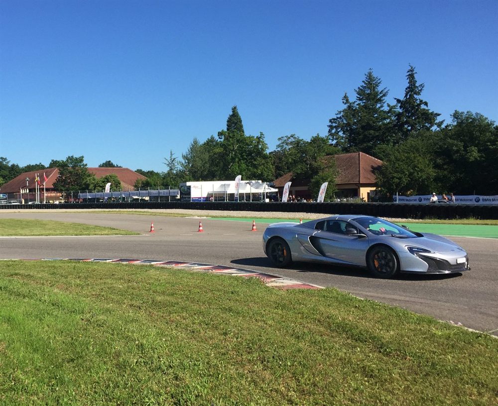 McLaren en sortie de virage devant les bâtiments du circuit