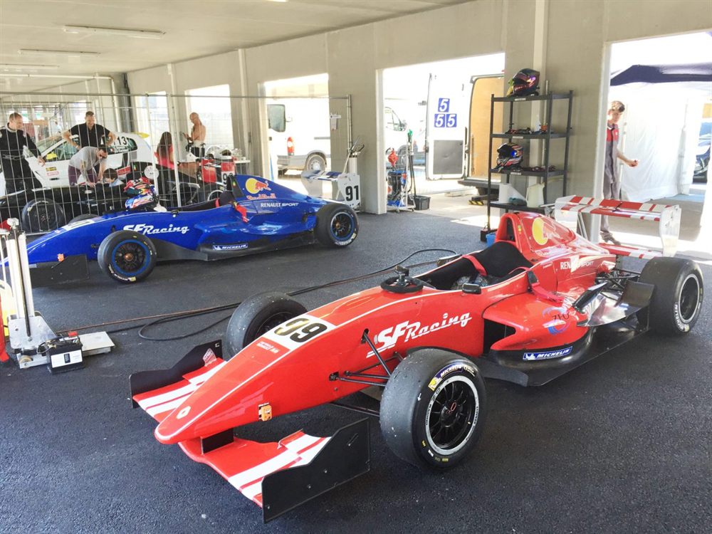 Deux monoplaces de Formule 4 dans un box du paddock