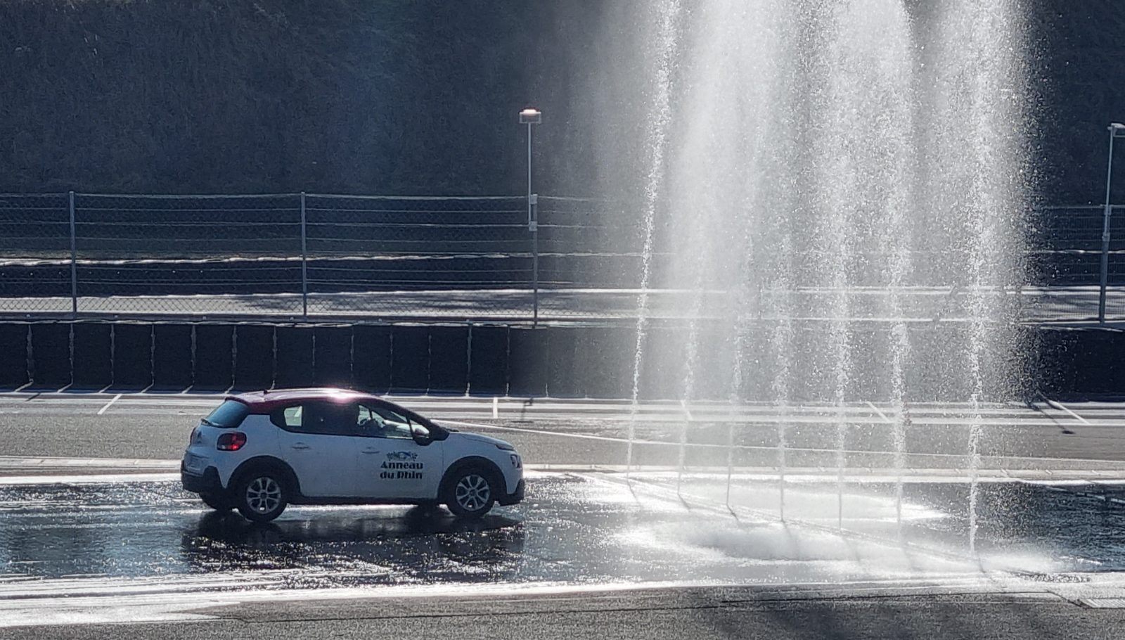 Voiture école traversant le rideau d'eau du plateau de sécurité routière