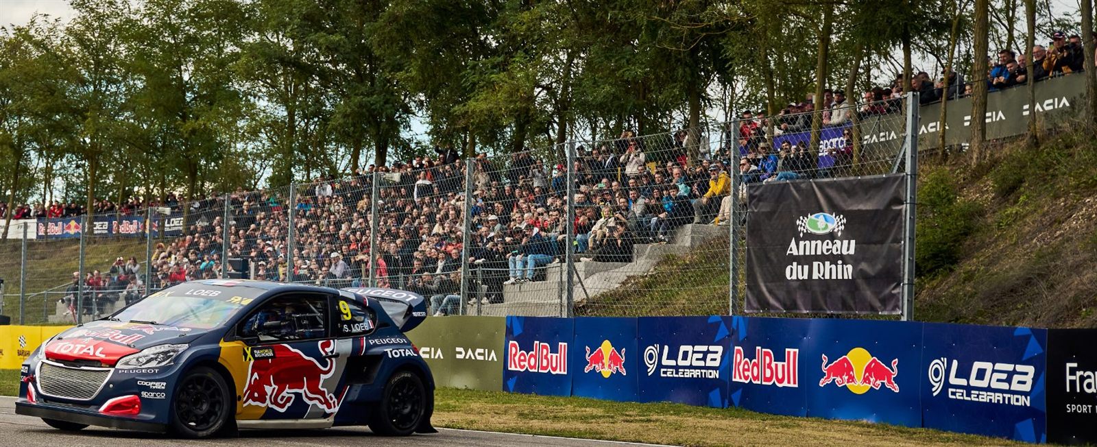 Tribunes garnies de public devant une voiture de rallycross en piste