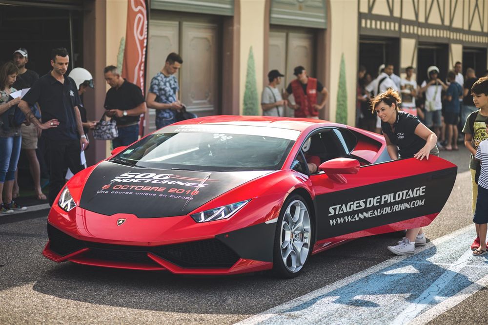 Lamborghini Huracán aux couleurs de l'Anneau du Rhin devant les stands, portière ouverte avant une session