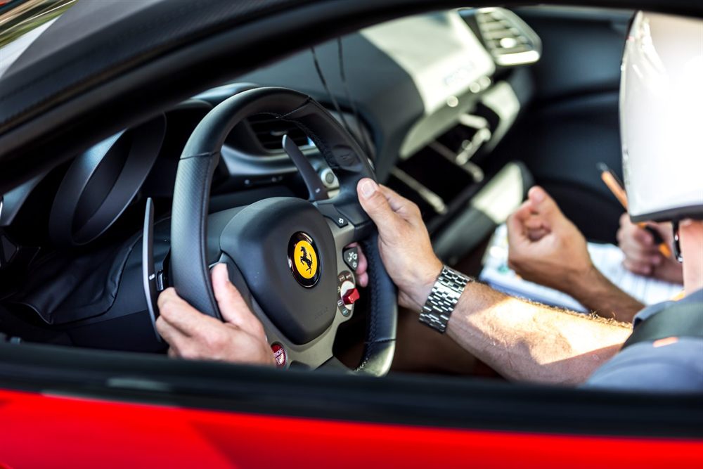 Mains au volant d'une Ferrari, instructeur à droite