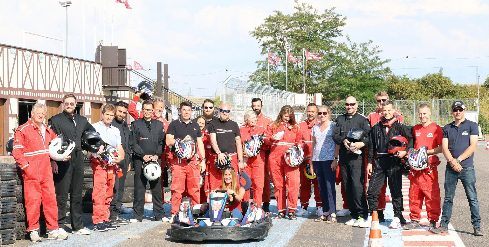 Groupe en combinaison posant devant un kart avant les sessions