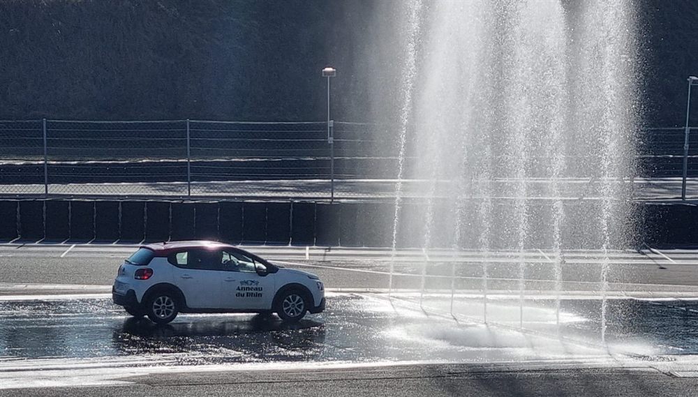 Voiture école sur le plateau sous les rampes d’arrosage
